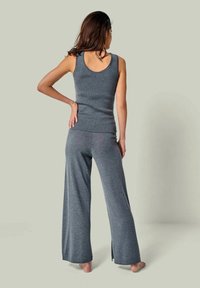 Graues gestricktes Tanktop und weit geschnittene Hose, mit geripptem Textur und Seitenschlitzen an der Hose. Freizeitlook aus leichtem Stoff ohne sichtbare Muster.