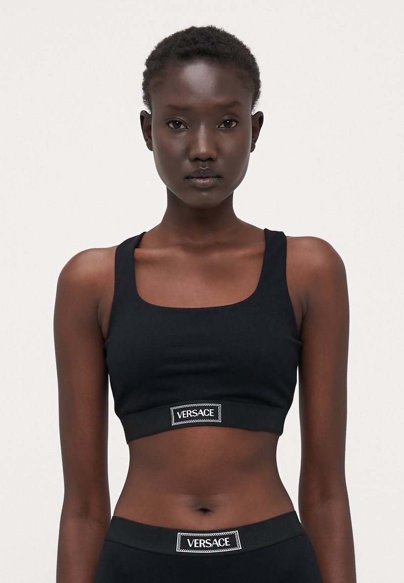 Sort cropped tank top lavet af blødt stof, med en firkantet halsudskæring og et bånd med Versace-logoet i bunden.