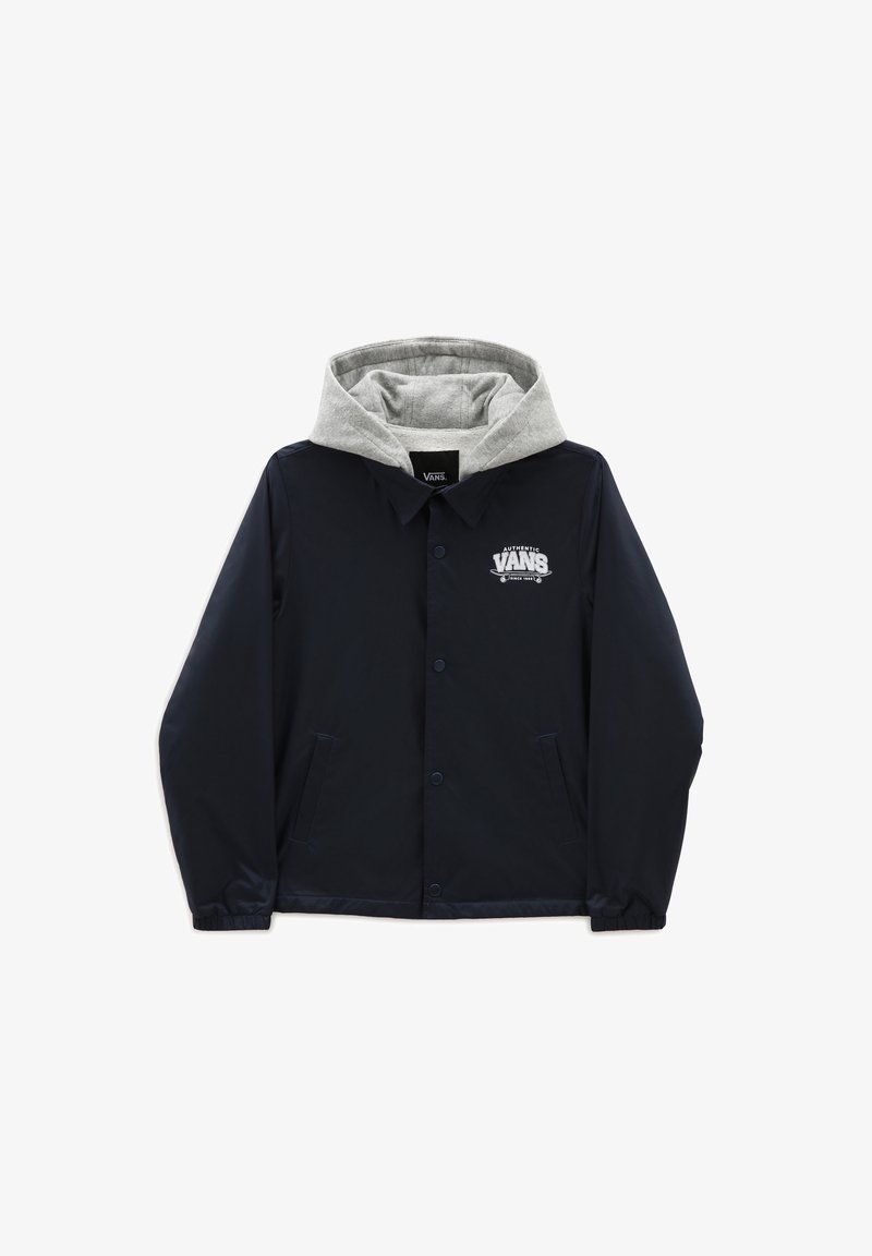 Námořnická modrá bunda vyrobená z voděodolného materiálu s šedou kapucí podšívkou, logem na hrudi, patentkami a postranními kapsami.