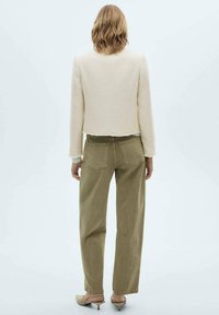 Cream textured jacket with long sleeves, cropped design. Olive green high-waisted pants with back pockets and straight legs.