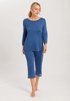 Blauwe loungewear set van zachte stof, bestaande uit een losse top met ronde hals en driekwartmouwen, en cropped broek met kantafwerking.