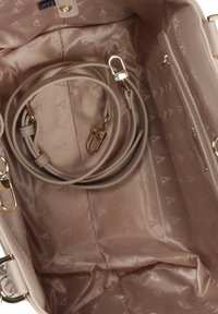 Interno di una borsa beige con foderatura in satin liscia, caratterizzato da un motivo impresso, una tracolla staccabile e dettagli in metallo dorato.