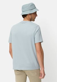 Lichtblauw katoenen T-shirt met korte mouwen, ronde hals en platte naden. Draagt een lichtblauwe bucket hat voor een coördinerende look.