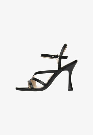 Sandale à talons hauts noire avec des brides fines autour de la cheville et un talon étroit. Présente une finition en cuir lisse et un design à bout ouvert.