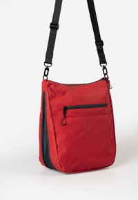 Rote Nylon-Schultertasche mit verstellbarem schwarzen Schultergurt, ausgestattet mit einer vorderen Reißverschlusstasche und kontrastierenden grauen Akzenten an den Seiten.