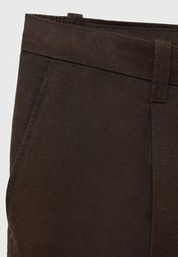 Pantalon en velours côtelé marron foncé avec une texture lisse, une coupe droite, des poches avant inclinées et une ceinture unie.