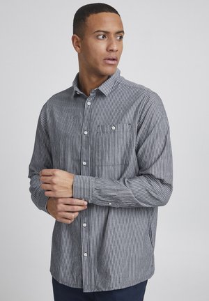 Gray striped button-up shirt with a small patch pocket, long sleeves, and a collar, features white buttons and a textured fabric.