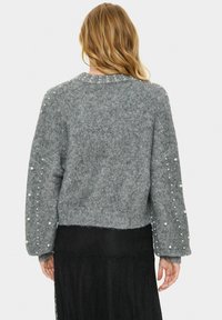 Szürke kötött pulóver tág, hosszú ujjal és gyöngy díszítéssel az ujjak mentén. Rövidített fazon, bordás nyakkal és aljjal.