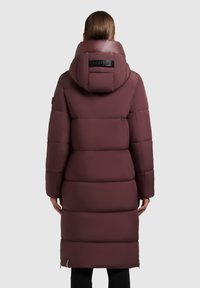 Geacă puf bordo cu guler înalt și glugă, având un design elegant, matlasat și un detaliu cu logo negru la gât.