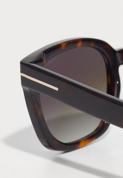 Brown tortoiseshell sunglasses with a thick frame, featuring gradient lenses and a thin metallic accent along the temples.