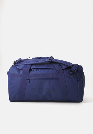 Navy duffel bag made of durable fabric, featuring dual handles, adjustable shoulder strap, and a zippered front pocket. Large logo imprinted.