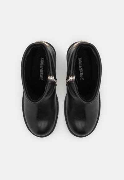 Musta nahkasaapas nilkkapituisena, sileällä pinnalla, sivu vetoketjulla ja pyöreällä varpaalla. Sisällä näkyvä brändäys. Kumipohja.