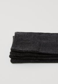 Calze nere lavorate a maglia, caratterizzate da una texture a coste, ripiegate ordinatamente, con un colore uniforme e senza dettagli visibili o decorazioni.