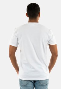 Camiseta blanca de manga corta, diseño clásico de cuello redondo, tela de algodón, textura suave, parte trasera lisa, combinada con jeans de color azul claro.