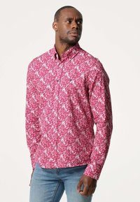 Overhemd met knopen in een roze bloemenpatroon op een witte achtergrond, gemaakt van katoen met een kraag en knoopsluiting.