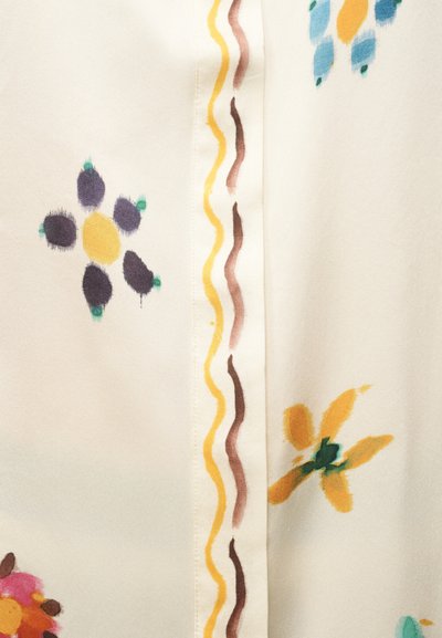 Λευκό ύφασμα με ζωγραφισμένα λουλουδάτα μοτίβα σε κίτρινο, μοβ, μπλε και πορτοκαλί, χωρισμένα με κάθετες κυματιστές γραμμές σε κίτρινο και καφέ.