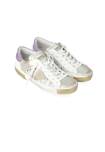 Sneakers bianchi a taglio basso con accenti viola sul tallone, patch beige con logo e suole consumate, posizionati e angolati a sinistra su uno sfondo bianco.