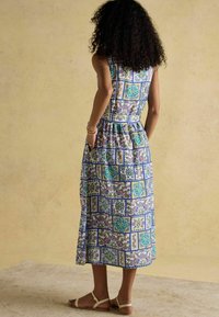 Maxi-Kleid mit floralem und geometrischem Druck in Blau, Grün und Cremefarben. Hergestellt aus leichtem Stoff, mit Taschen und einer taillierten Passform.