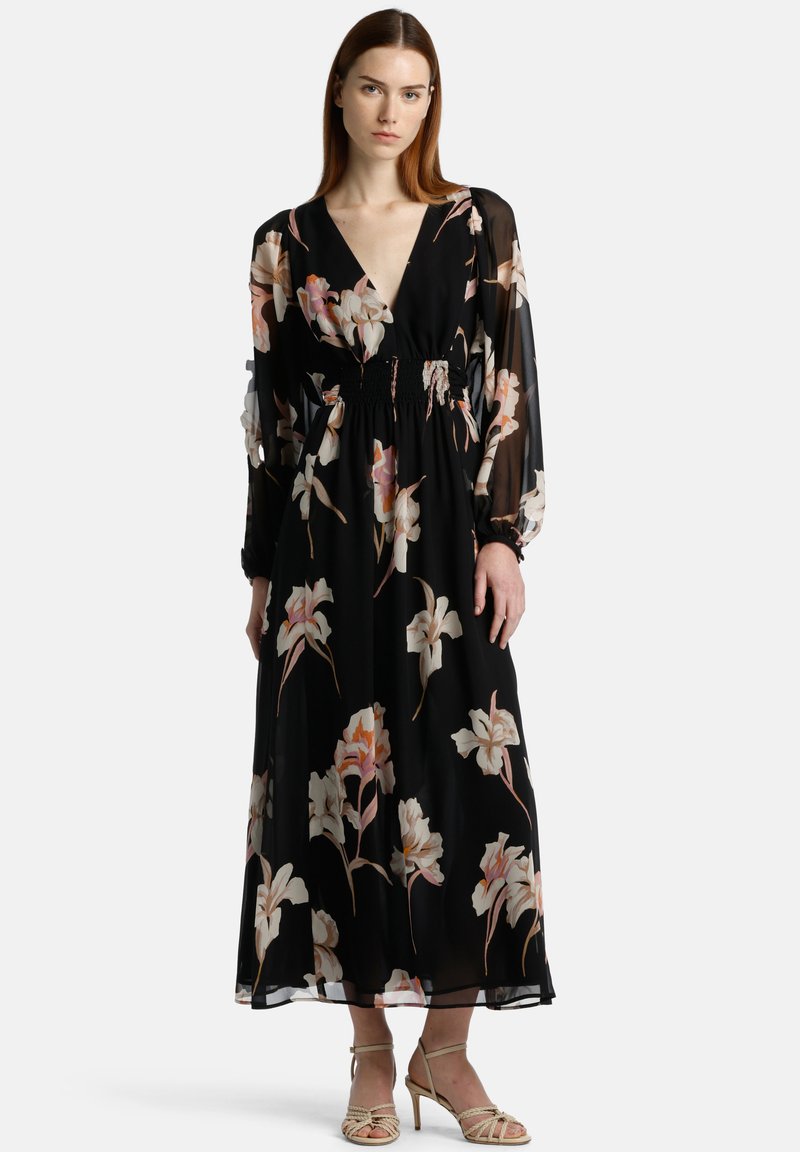 Rochie lungă neagră cu flori, cu decolteu adânc în V, model floral în nuanțe delicate, mâneci lungi din material transparent, talie plisată și țesătură ușoară.