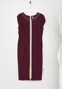 Robe bordeaux sans manches longueur genou avec une fermeture éclair verticale beige au centre et une bordure dorée autour de l'encolure, suspendue à un cintre transparent.