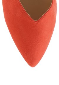 Jasnopomarańczowy zamszowy czółenek zakończony w czubek o eleganckim wzornictwie i gładkiej teksturze, z niskim wycięciem po bokach, które wydłuża sylwetkę.