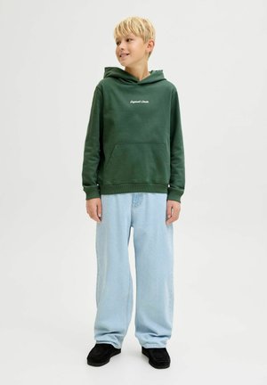 Felpa verde con cappuccio e tasca frontale, abbinata a jeans larghi blu chiaro e scarpe nere, con testo ricamato bianco sul petto.