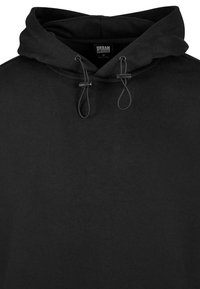 Sudadera negra hecha de algodón suave. Presenta una capucha con cordón, diseño elegante y sin logotipos ni patrones visibles. Estilo simple y minimalista.