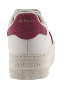 Sneaker bianco con un accento in camoscio bordeaux sul tallone. Presenta una suola in gomma testurizzata e un logo impresso sul tallone. Parte superiore in pelle liscia.