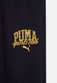 Black fabric features a bold yellow "PUMA sports club" logo. Text has a distressed look with a leaping puma silhouette below.