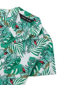 Camicia a maniche corte con colletto, caratterizzata da un vivace motivo di dinosauro verde con occhiali da sole, circondato da motivi di foglie tropicali su uno sfondo bianco.