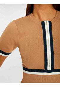 Top aderente color sabbia con texture a coste, caratterizzato da un colletto con mezza zip e dettagli a righe blu e bianche sulle maniche e in vita.