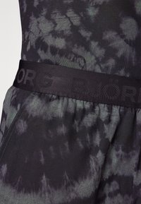 Črno in sivo tkanino z efektom tye-dye z teksturiranim zaključkom; vsebuje širok elastičen pas z zlogom "B.JÖRG" embosiranim v črni barvi.