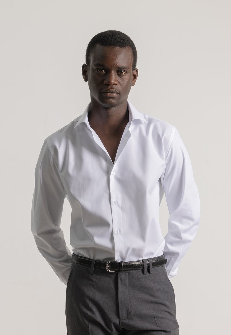 Camisa blanca con cuello clásico, cierre de botones y mangas largas, combinada con pantalones gris oscuro y un cinturón de cuero negro.