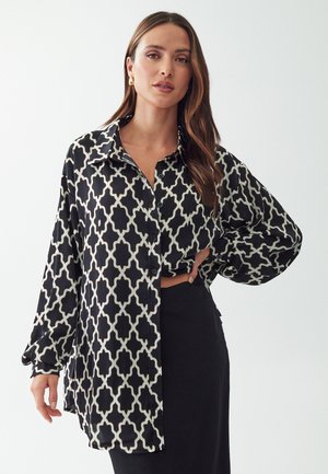 Camicia a maniche lunghe, con motivo bianco e nero, dotata di bottoni sul davanti, colletto e vestibilità comoda. Presenta un design geometrico e tessuto morbido.