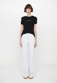 Black short-sleeve t-shirt with "MAX&Co." logo, paired with light blue wide-leg pants and beige slip-on shoes on a plain background.