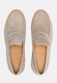 Mocassini in suede beige con una texture liscia, punta arrotondata, dettaglio della cucitura sollevata e una soletta in pelle color tostato. Nessun hardware o accentuazione visibile.