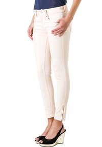 Ljust rosa skinny jeans med en mjuk yta, dragkedjedetaljer vid anklarna och traditionella fickor, kombinerade med svarta platåskor.