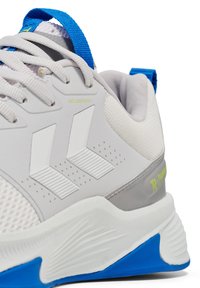 Scarpa da ginnastica bianca con accenti blu. Presenta materiali in rete e lisci, sistema di fissaggio dei lacci e suola testurizzata con elementi blu e grigi.