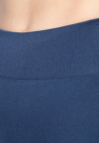 Nahaufnahme einer Schulter einer Person, die ein blaues, geripptes, schulterfreies Kleidungsstück trägt.