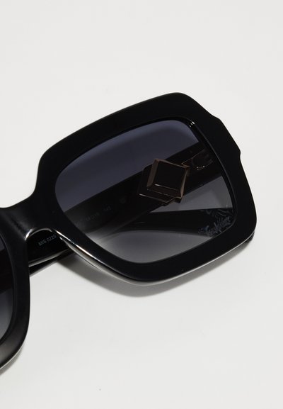 Mustad üleööpäikeseprillid ruudukujulise raamiga, gradient-läätsed ja metalliline detail templil. Sile pind, julge disain.