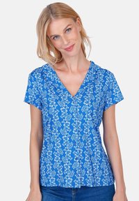 Blue floral blouse with short sleeves, V-neck, and button front. Features small white flower patterns and a soft, textured fabric.