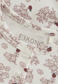 Off-white jumpsuit med blommönster i dammig rosa, med små nyckelpiga-accenter, knäppning och mjukt, strukturerat bomullstyg.