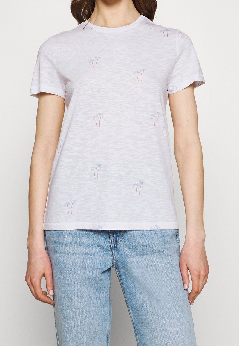 T-shirt blanc à manches courtes avec un tissu texturé et de petites impressions de palmiers en bleu et orange. Col rond et coupe régulière.