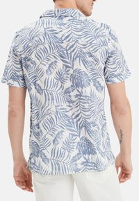Camisa de manga corta con un patrón de hojas en azul y blanco, hecha de tela ligera, con un corte relajado y diseño de cuello abierto.