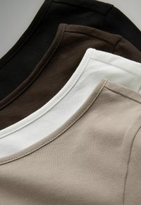 Tri plain t-shirt majice s okruglim izrezom u crnoj, smeškoj i bež tkanini, koje ističu glatku teksturu i šavove na izrezima.