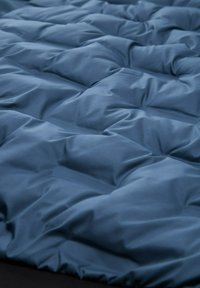 Niebieska pikowana pościel z miękką, teksturowaną powierzchnią. Posiada puszyste, wypukłe sekcje zapewniające izolację i komfort.