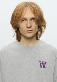 Grå sweatshirt lavet af bomuld, med et lille lilla logo på venstre bryst. Rund halsudskæring, afslappet pasform og blød tekstur.