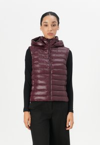 Bordeaux puffer vest med glidelås og hette, med horisontale kviltede sømmer og et logo-patch øverst til venstre.