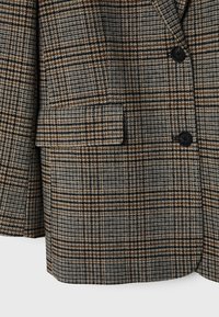 Blazer à carreaux marron, noir et beige avec deux boutons noirs et une poche à rabat en bas à l'avant.