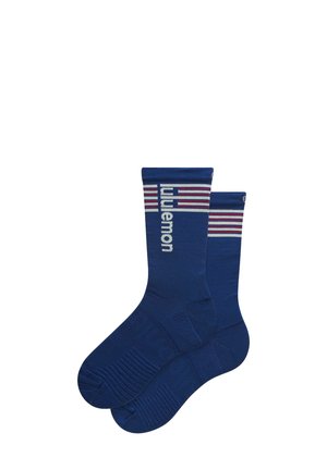 Een paar blauwe sokken met geribbelde textuur, voorzien van de tekst "lululemon" en rode en witte strepen nabij de bovenkant van de boord.